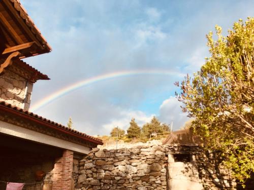 un arco iris en el cielo sobre una pared de piedra en Artesano I y III, en Navarredonda de Gredos