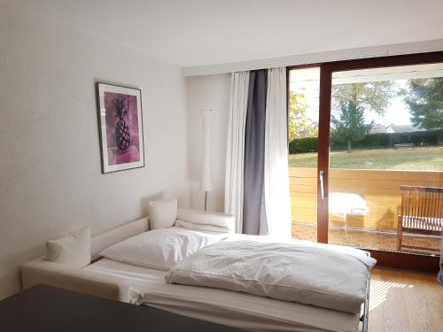 1 cama blanca en un dormitorio con ventana en Ferienwohnung im Schwarzwald Oberwiesenhof, en Seewald