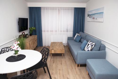een woonkamer met een blauwe bank en een tafel bij Apartament Silva View in Hel