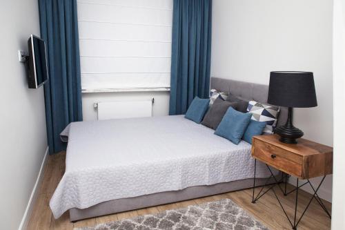 a bedroom with a bed with blue curtains and a lamp at Apartament Silva View in Hel