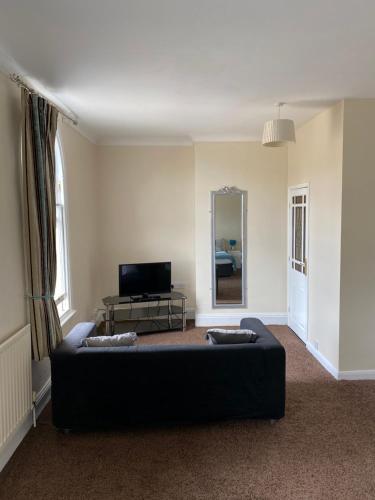 a living room with a black couch and a mirror at The Victoria in Saltburn-by-the-Sea