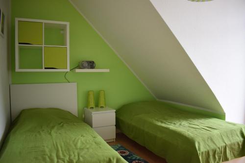een slaapkamer met groene muren en 2 aparte bedden bij Detailverliebt in Dornumersiel in Dornum