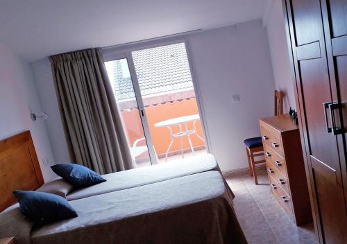 een slaapkamer met een bed en een raam met een tafel bij EIVISSA in Malgrat de Mar