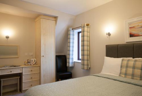 a bedroom with a bed and a desk and a chair at Lochview House in Fort William