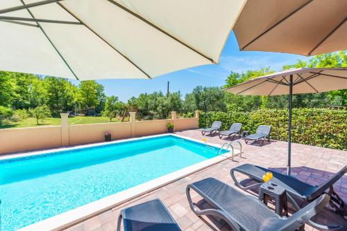 a swimming pool with chairs and umbrellas next to a swimming pool at Nelly Apartments in Privlaka