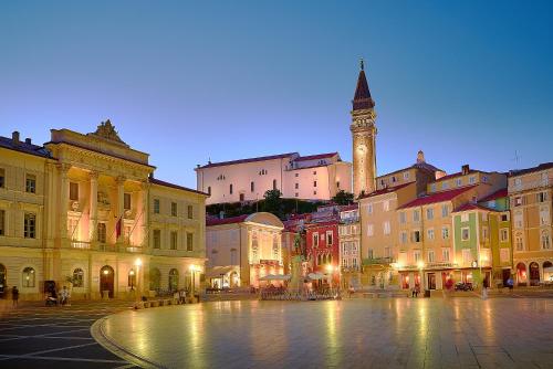 a city square with a clock tower at night at Altana Mario in Piran