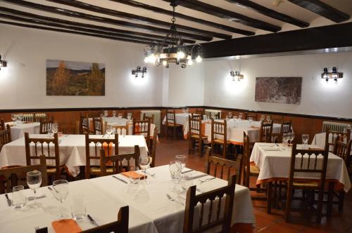 una sala da pranzo con tavoli e sedie bianchi di Hostal de Montaña la Casa Grande a Nogueruelas