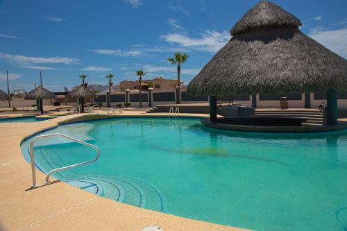 een zwembad met een rieten parasol en een resort bij Linda Vista 513 in Puerto Peñasco