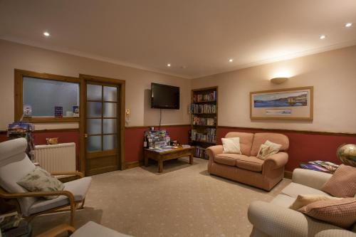 a living room with a couch and chairs and a tv at Lochview House in Fort William