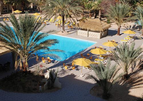 an overhead view of a swimming pool with umbrellas and palm trees at Sahara Douz in Douz