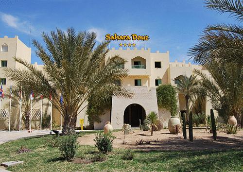 a large building with palm trees in front of it at Sahara Douz in Douz