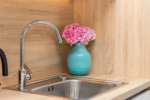a blue vase with pink flowers sitting on a kitchen sink at Apartman Ružica in Pučišća