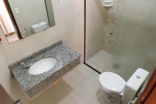 a bathroom with a toilet and a sink and a shower at Hotel Marazul in Cananéia
