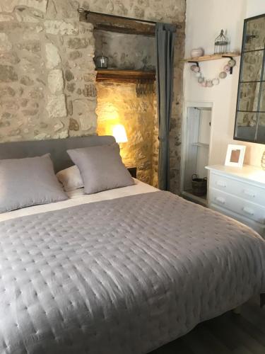 a bedroom with a bed and a stone wall at Au cœur de Céreste in Céreste