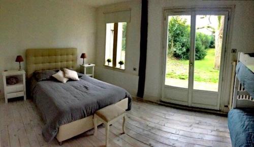 een slaapkamer met een bed en een glazen schuifdeur bij Détente à la compagne piscine chauffée billard et baby foot in Caugé