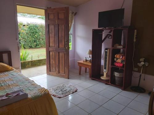 1 dormitorio con 1 cama y puerta con TV en Posada Rural Oasis en Caño Negro