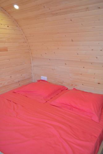 Cama grande en habitación de madera con sábanas rojas en LA ROULOTTE VITICOLE, en Cauro