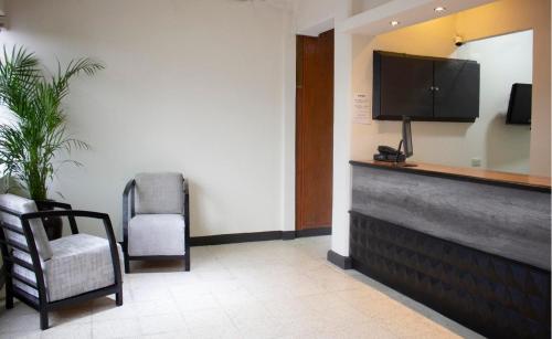 una sala de espera con TV y silla en Hotel Winn Comfort en Tlaxcala de Xicohténcatl