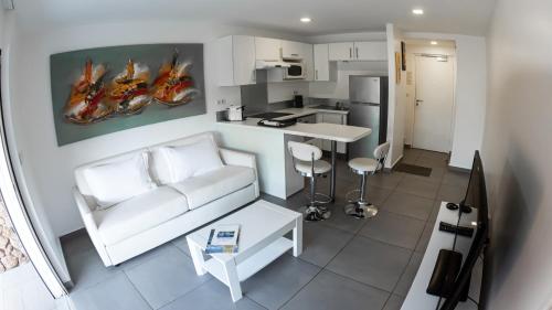 a living room with a white couch and a kitchen at Moorea Sunset Beach in Haapiti