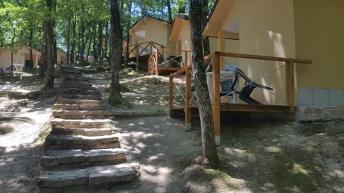 a house with a set of stone steps next to trees at Ваканционно селище СБХ in Shkorpilovtsi