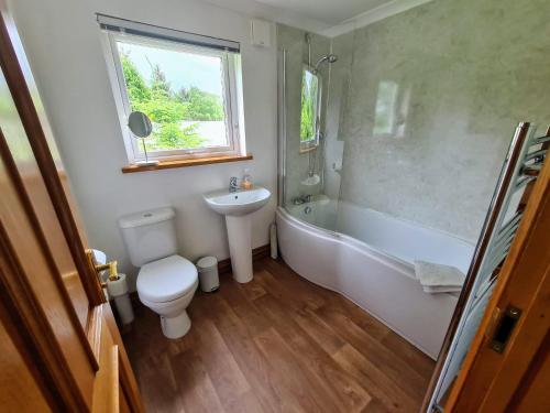a bathroom with a toilet and a tub and a sink at The Haven in Keswick