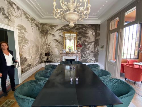 une femme debout dans une pièce avec une table et des chaises dans l'établissement Maison Blanche Chartres - Maison d'hôtes 5 étoiles, à Chartres
