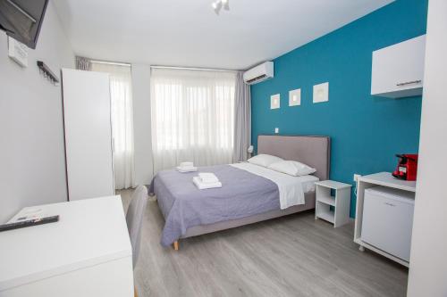 a bedroom with a bed and a blue wall at Raise Boutique Rooms in the Center of Athens in Athens