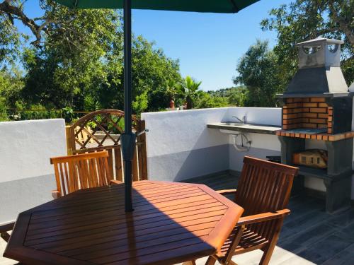 a wooden table and chairs with an umbrella on a patio at Quinta dos Netos in Tavira