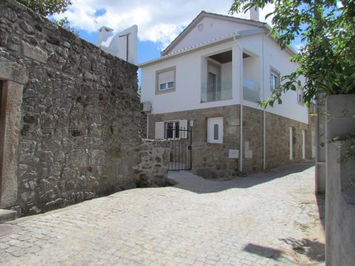 a house with a stone wall next to a building at Casa das Nações in Donas
