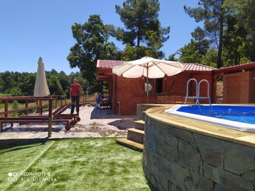 a person standing next to a swimming pool with an umbrella at Casa das Vinhas Velhas by Casa do Poço in Peso da Régua