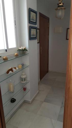 a hallway with glass shelves in a room with a window at Bonito Ático en el centro de la ciudad in Sanlúcar de Barrameda
