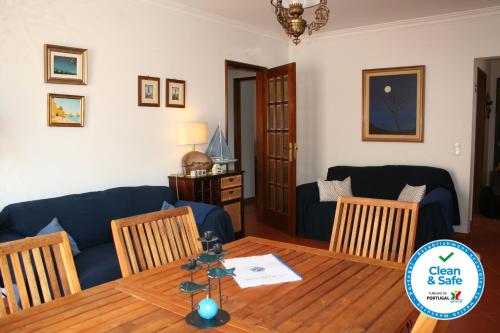 uma sala de estar com uma mesa e um sofá azul em Cezimbra Guest House em Sesimbra