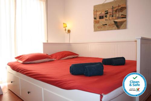 - une chambre dotée d'un grand lit avec des draps et des oreillers rouges dans l'établissement Cezimbra Guest House, à Sesimbra