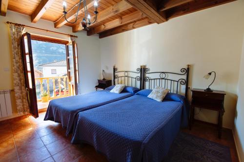 a bedroom with a bed with a blue comforter at Casa Rural La Galana in Sames