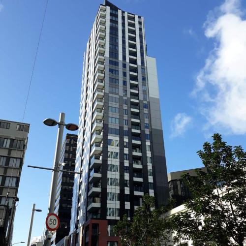 een hoog gebouw met veel ramen aan een stadsstraat bij Central location of Auckland Central in Auckland
