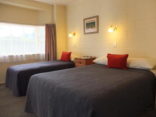 Cette chambre comprend 2 lits et une fenêtre. dans l'établissement Colonial Court Motel, à Cambridge