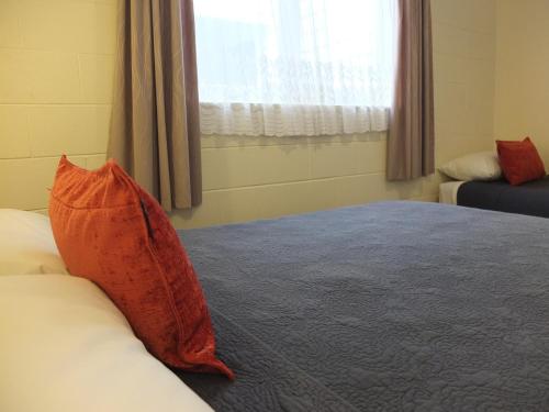 a bedroom with a bed with a red pillow on it at Colonial Court Motel in Cambridge