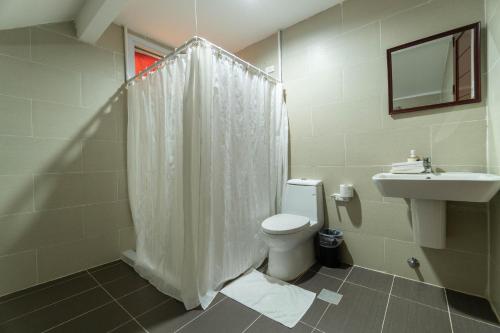 a bathroom with a white shower curtain and a toilet at One Averee Bay Hotel in Coron