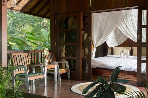 a bedroom with a bed and a table and chairs at Rasasvada cottages in Uluwatu