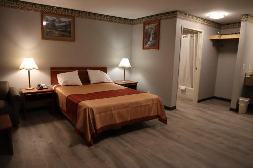 ein Schlafzimmer mit einem Bett, zwei Lampen und einer Tür in der Unterkunft Express Inn & Suites Eugene in Eugene