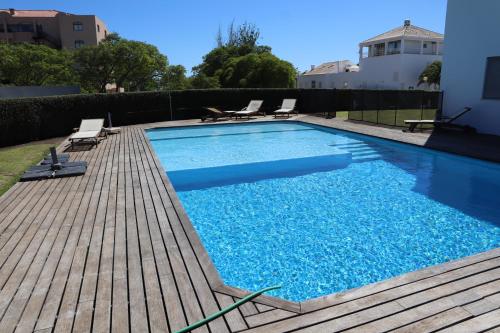 a swimming pool with chairs and a wooden deck at Villa dos Salgados - Beachfront, 6 Golf Courses, 6BDR in Guia