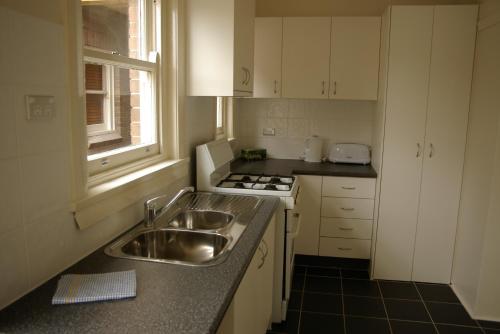 a small kitchen with a sink and a stove at Accommodation Sydney Rockdale - 2 Bedroom Pet Friendly Budget Apartments near Rockdale Station and Brighton Le Sands Beach in Sydney