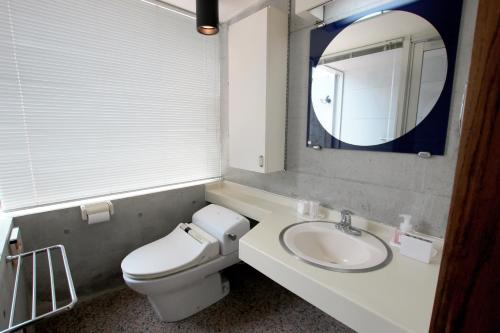 a bathroom with a toilet and a sink and a mirror at Kaze -SEVEN Hotels and Resorts- in Higashi