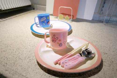 a plate with a pink coffee cup and a toy gun at Kaze -SEVEN Hotels and Resorts- in Higashi