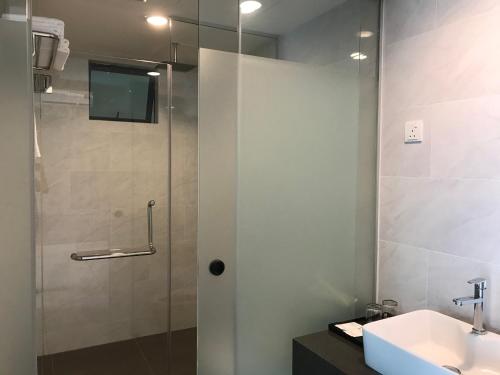 a shower with a glass door next to a sink at Dandelion Inn in Simpang Pulai