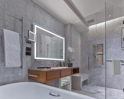 a bathroom with a tub and a sink and a mirror at Grand Hyatt Manila in Manila