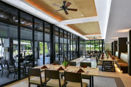 a restaurant with tables and chairs and large windows at Seda Lio in El Nido