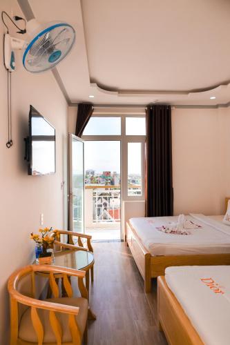 a hotel room with two beds and a balcony at Khách Sạn Phương Khuê in Ấp Bình Hưng