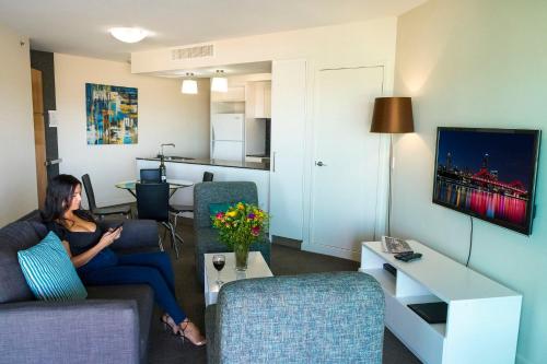 a woman sitting on a couch in a living room at Evolution Apartments in Brisbane