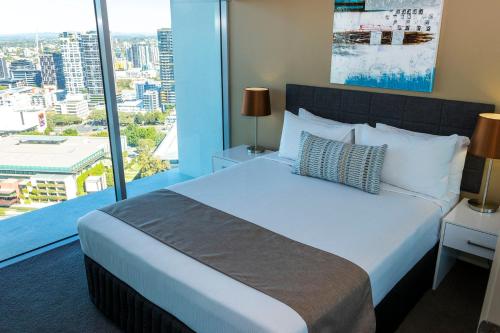 a bedroom with a large bed and a large window at Evolution Apartments in Brisbane